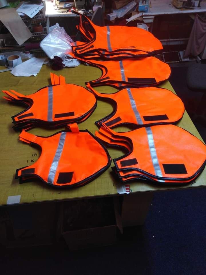 Fluorescent orange dog vests laid out in a row